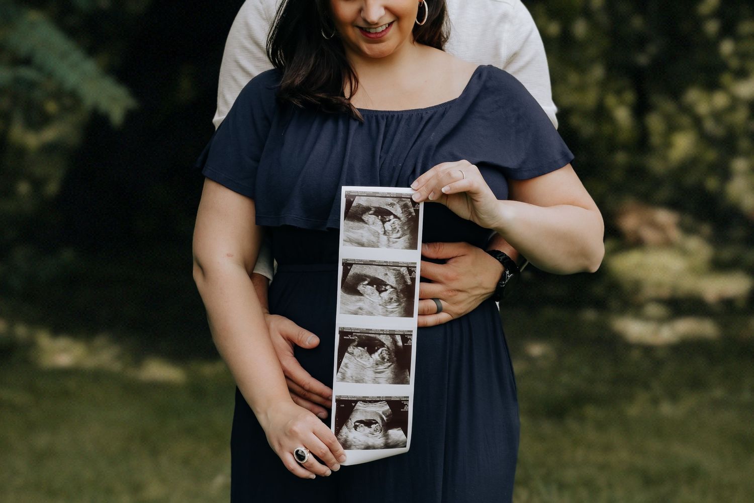 Person holding ultrasound photos during pregnancy announcement photoshoot.