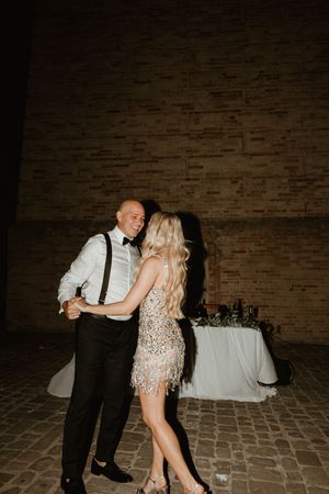 Couple dancing together on a brick floor during their wedding reception.