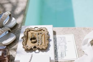 Ornate gold frame and papers arranged on a white surface with a turquoise background.