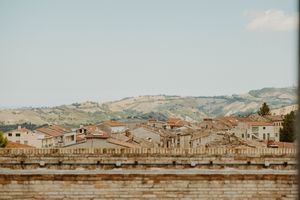 Panoramic view of an Italian hillside town with terracotta roofs against a blue sky.