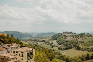 Rolling green hills and traditional buildings in the Tuscan countryside.