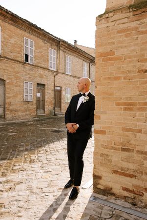 Wedding party members stand against a rustic stone wall in formal attire.