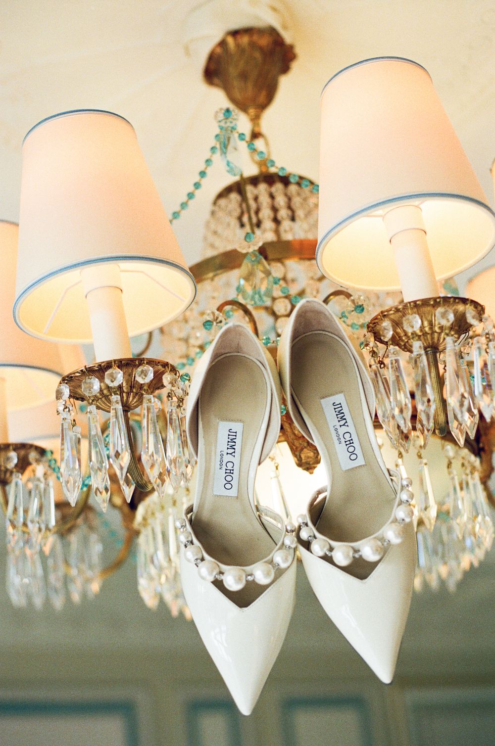 Jimmy choos with pearls hanging on Ritz Paris chandeliers. RItz Paris bride. Editorial Paris wedding photography.