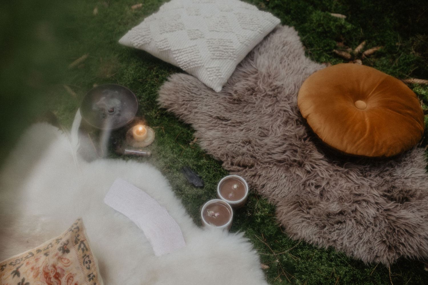 Gemütliche Hygge-Szene mit flauschigen Kissen, Kerzen und warmem Licht schafft eine einladende Herbstatmosphäre.