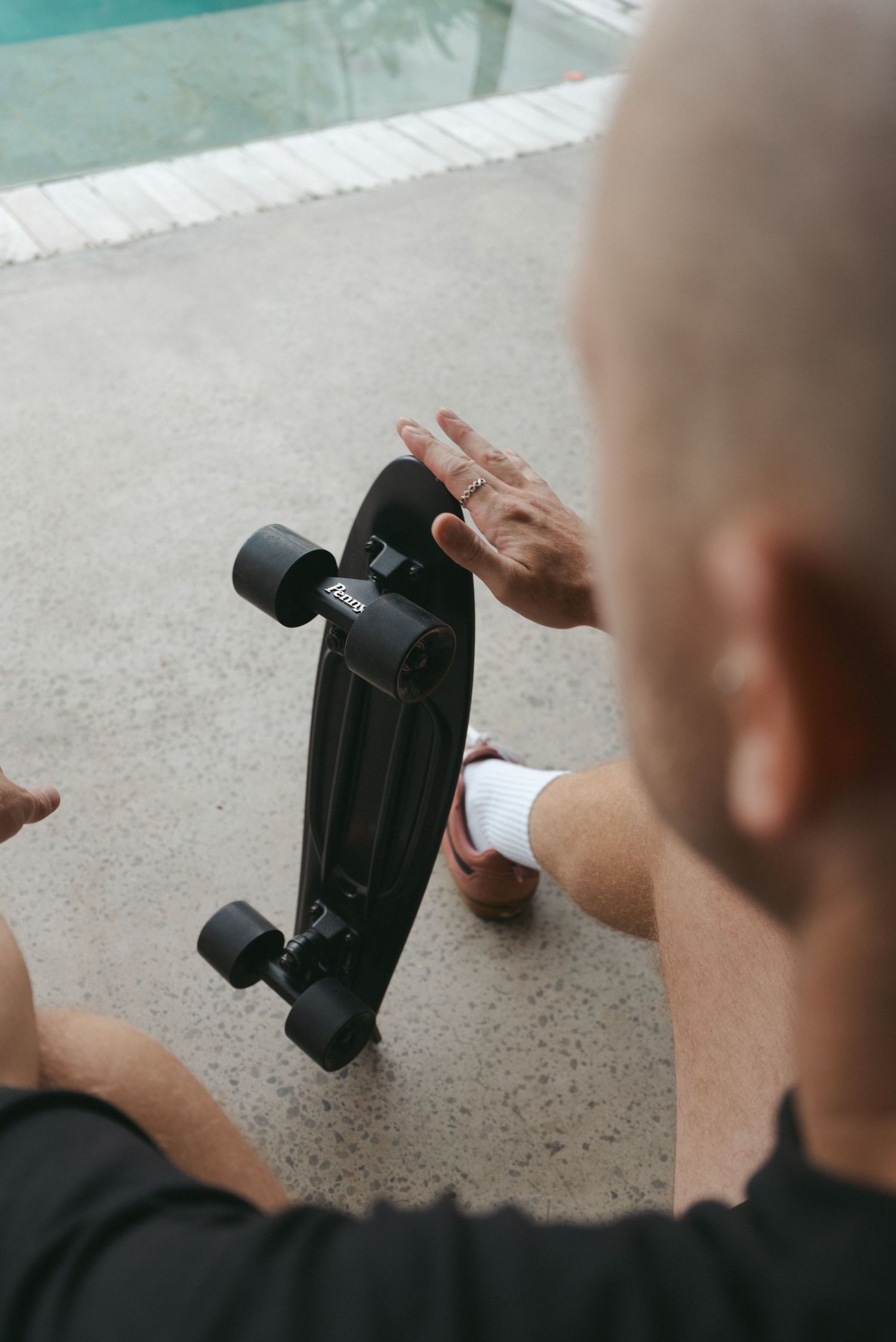 Person filming with handheld camera gimbal stabilizer outdoors near a pool.