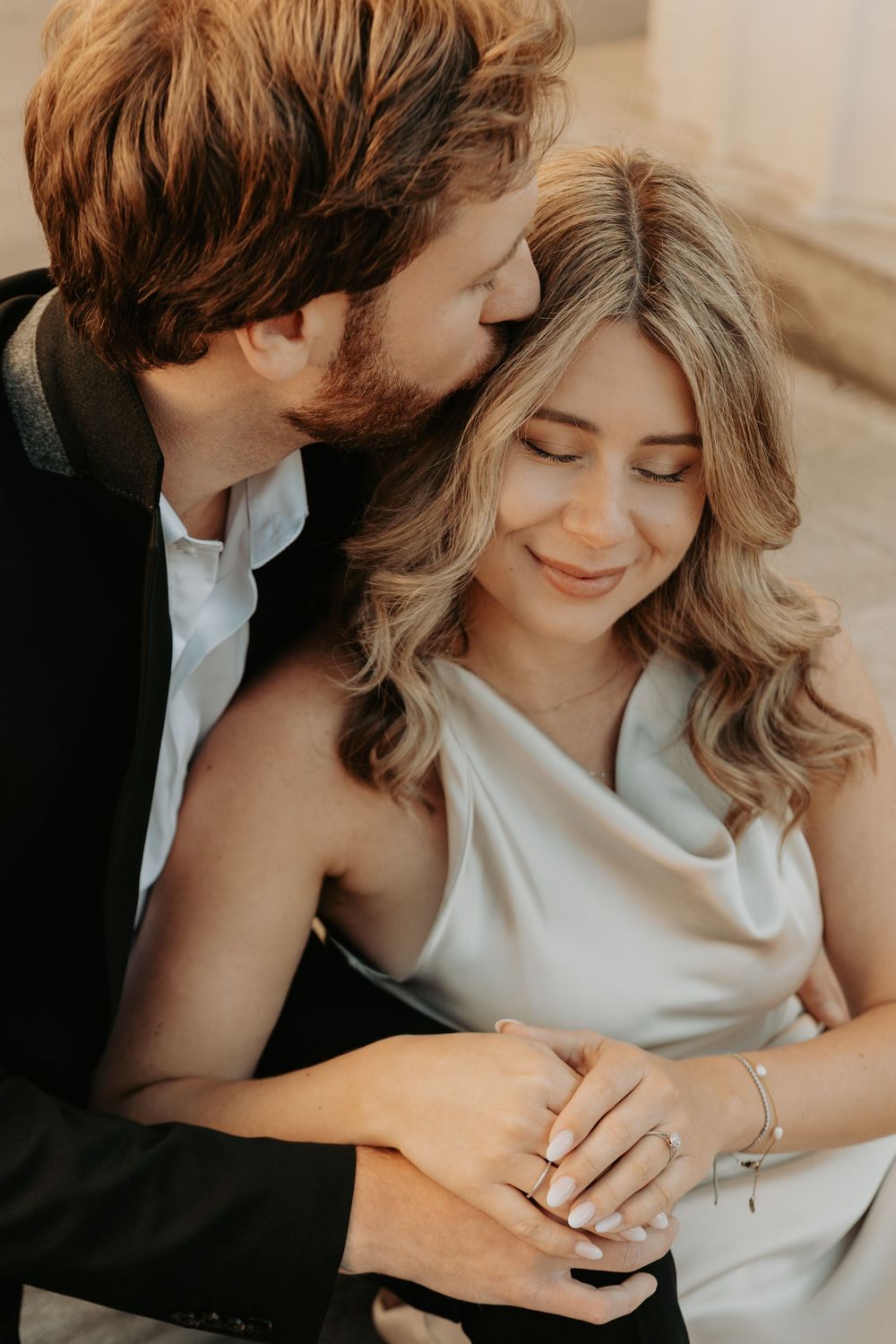 Close-up shots of couple sharing intimate moments while showcasing engagement ring in natural lighting.