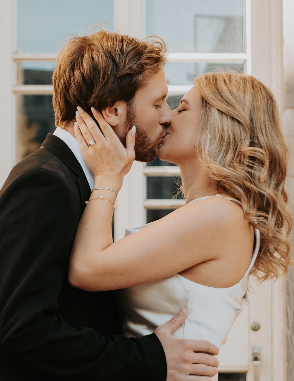 A romantic moment shared between a couple in formal attire, with the bride wearing white and groom in black suit.