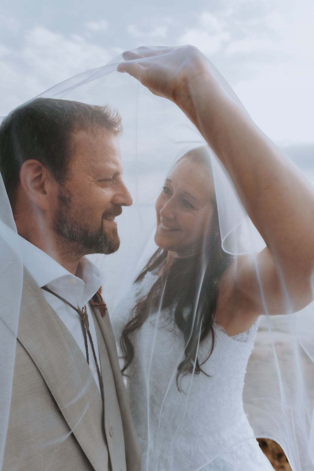 A romantic couple in wedding attire share an intimate dance moment under soft lighting.