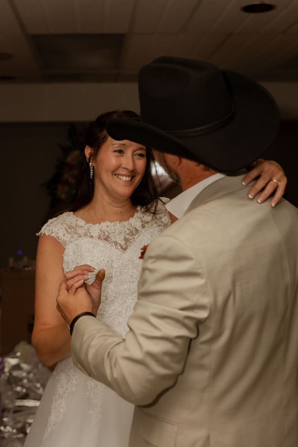 A couple shares a romantic dance at their wedding reception, with the bride wearing a beautiful lace dress.