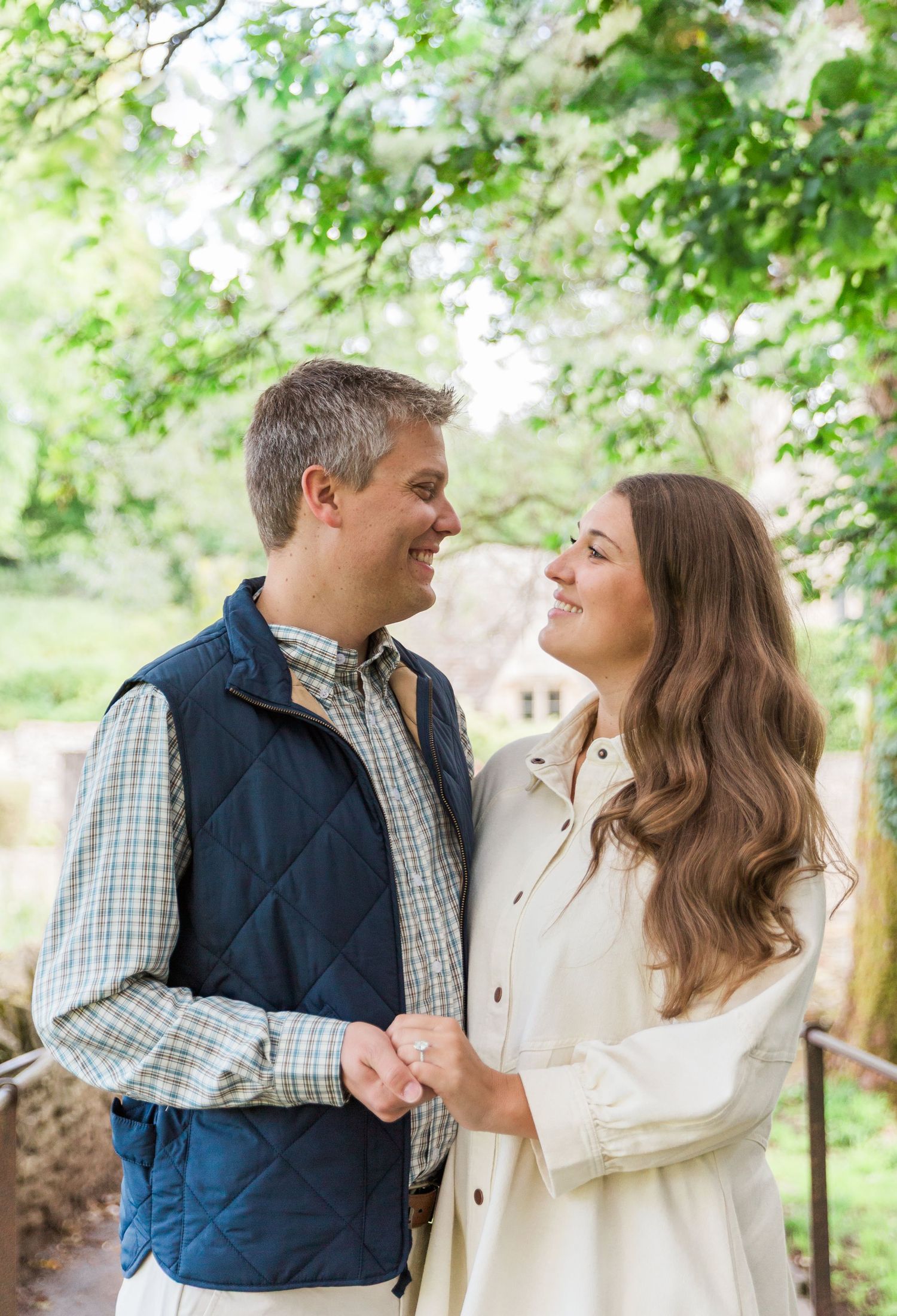 A couple share joyful laughter while embracing at Bibury Cotswolds - Proposal Session Hayley Elizabeth Photography