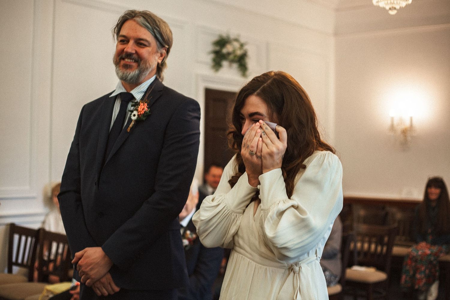 Bride crying tears of joy as groom smiles during vows at Leatherhead Registry Office by Dominique Lauren Photography