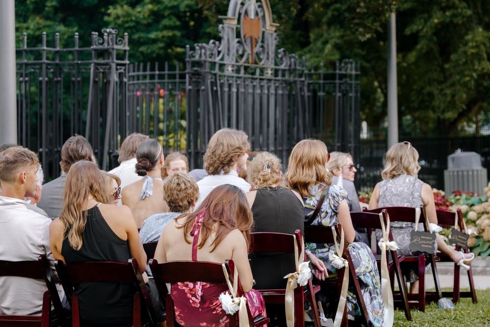Wedding party guests enjoying an outdoor reception with tables and chairs set up in a garden setting.