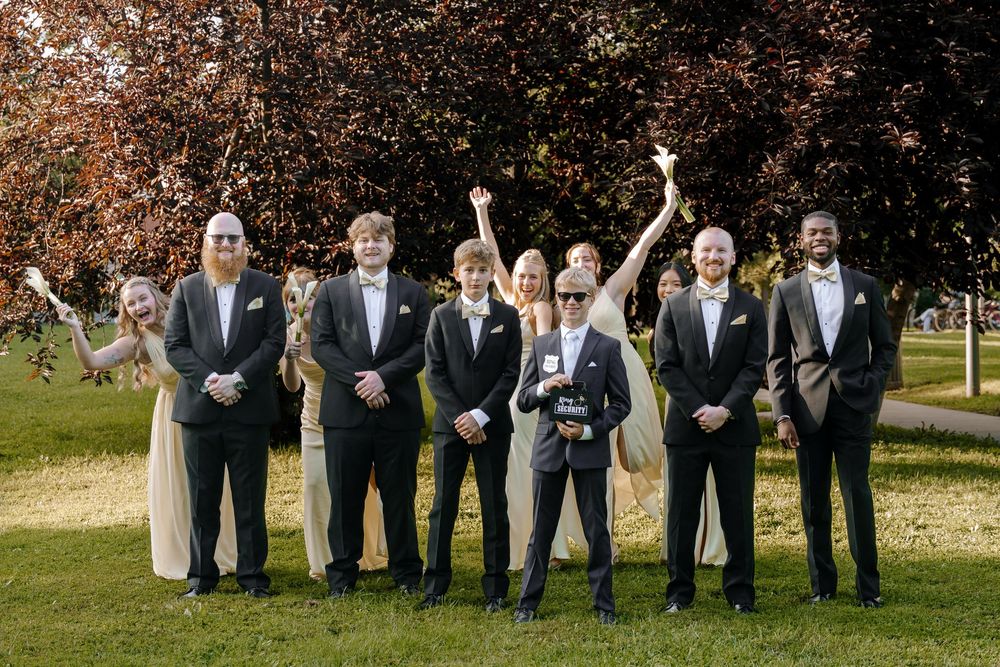 Wedding party in formal attire poses together outdoors in a playful jumping sequence.