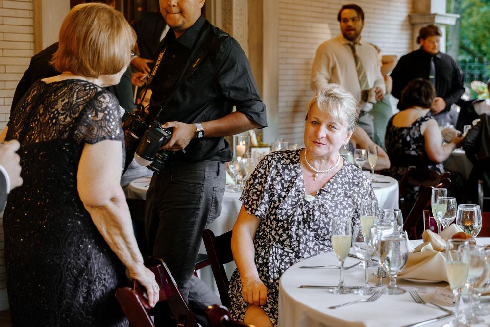 Guests seated at long tables engage in conversation during an indoor dining event.