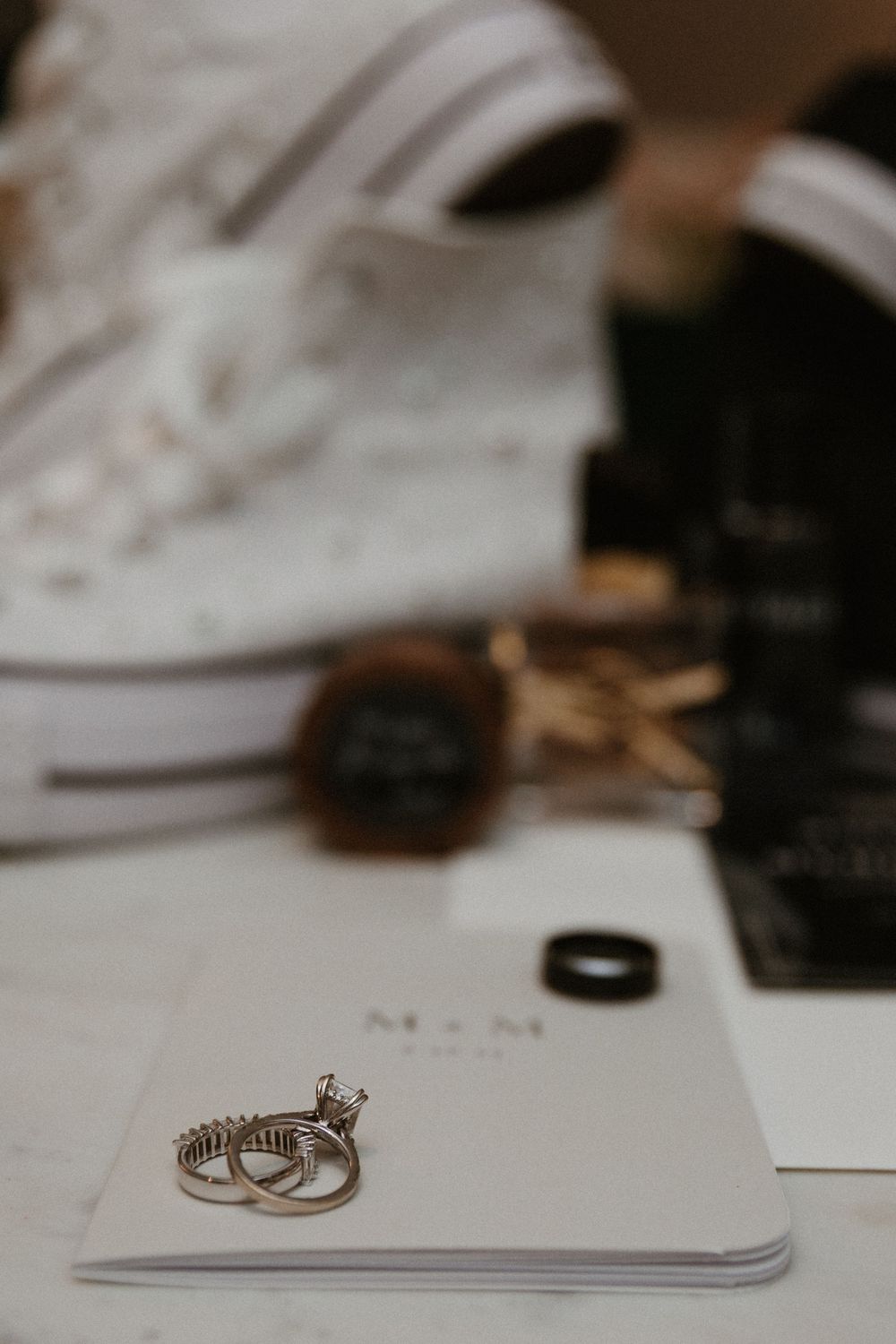 Wedding rings and stationery arranged on white surface with elegant minimalist styling.