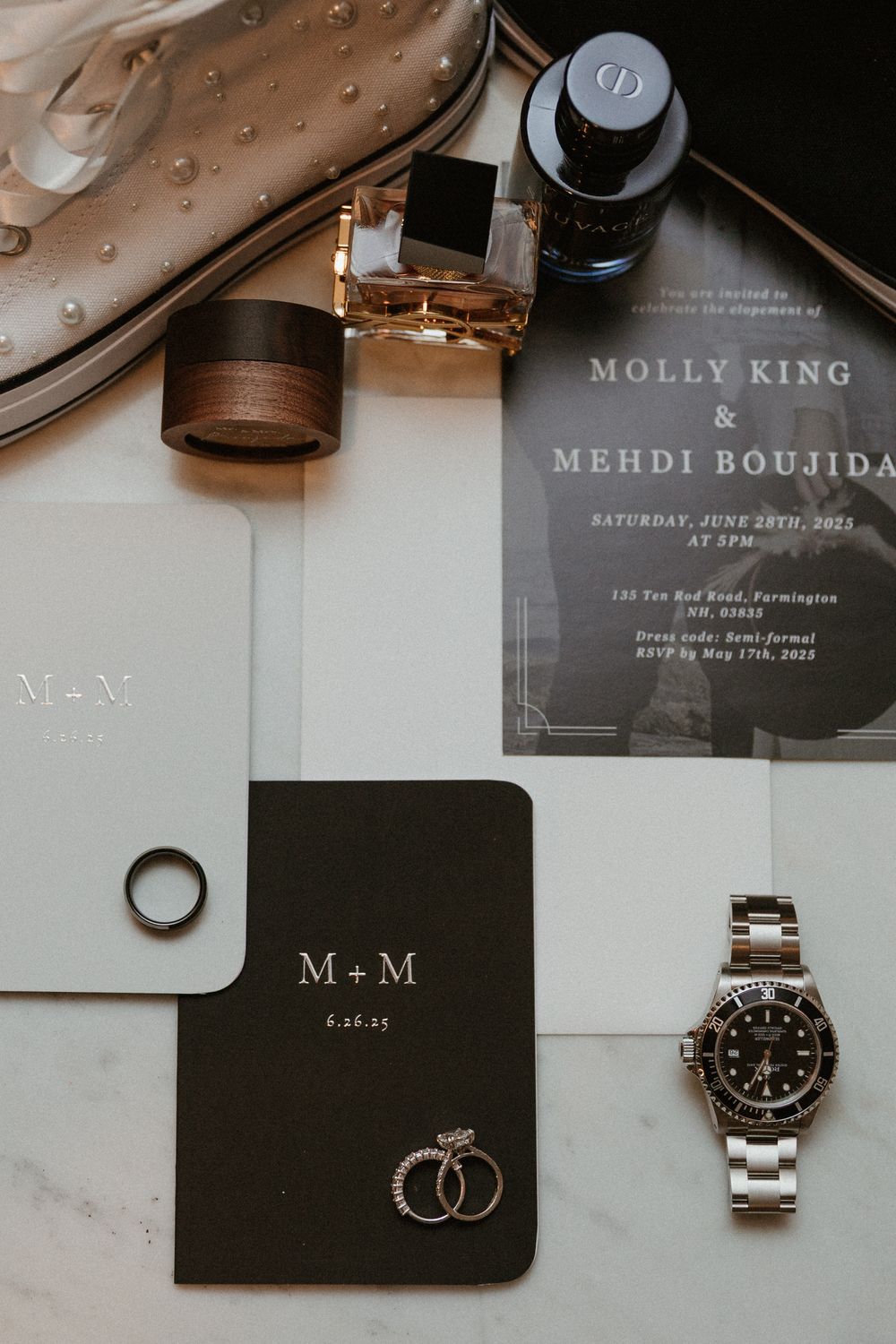 Luxury watch and wedding rings displayed with modern black and white stationery.