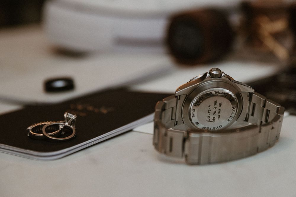 Close-up of silver watch and wedding rings styled with minimalist details.