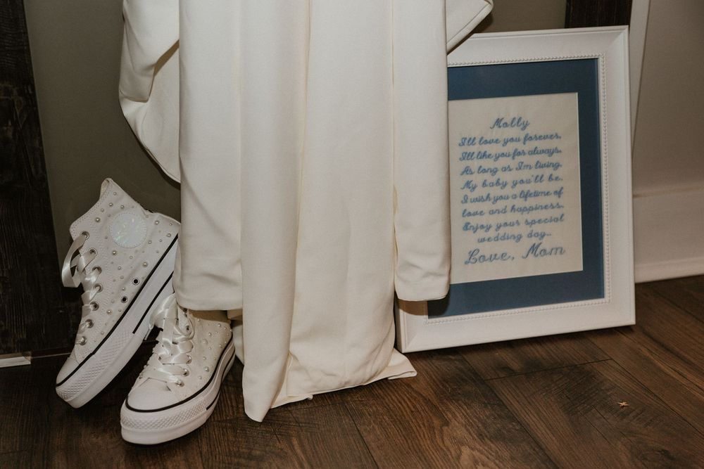 Close-up view of white Converse sneakers beneath a flowing white wedding dress.