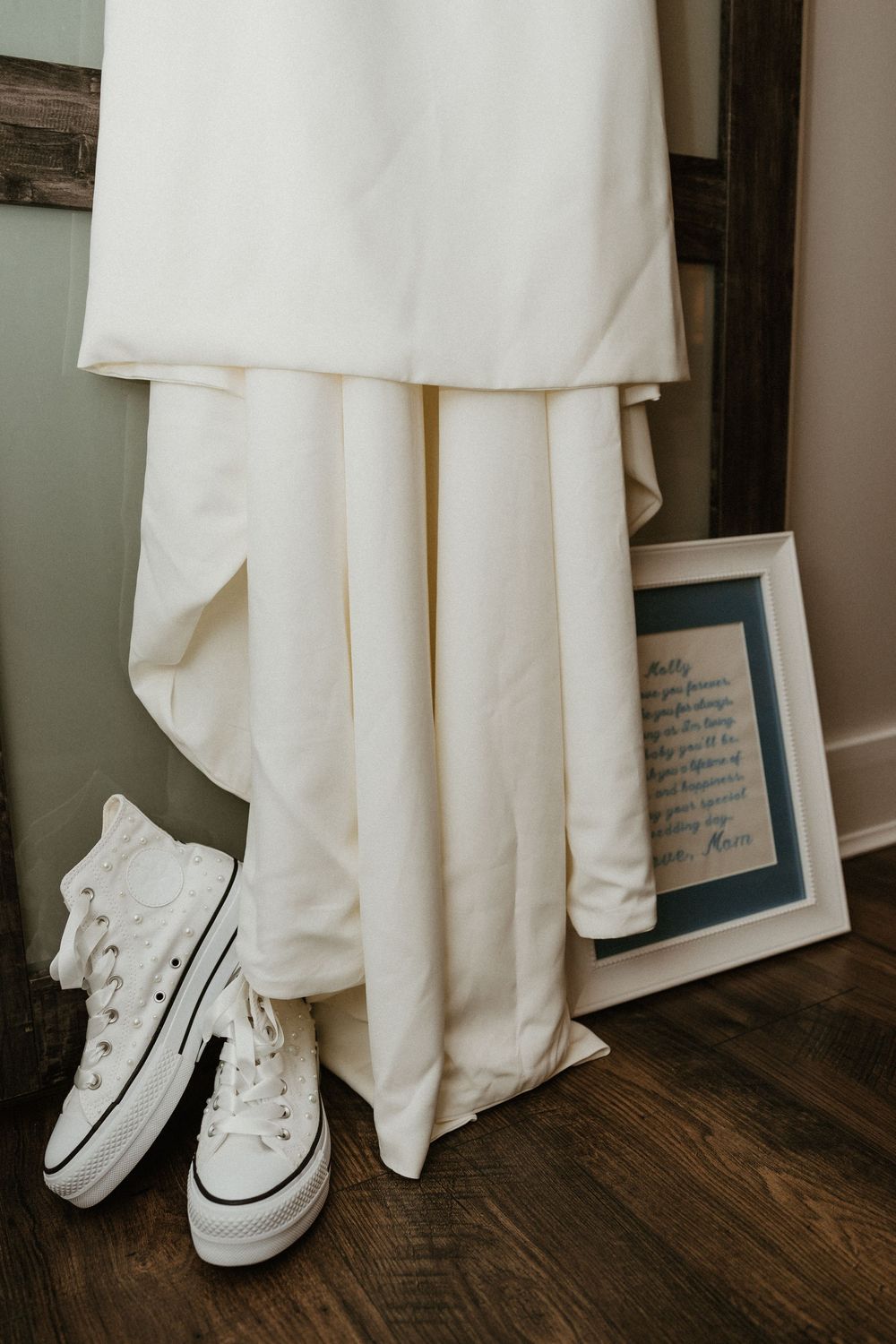 White bridal outfit paired with classic white Converse sneakers on a wooden floor.
