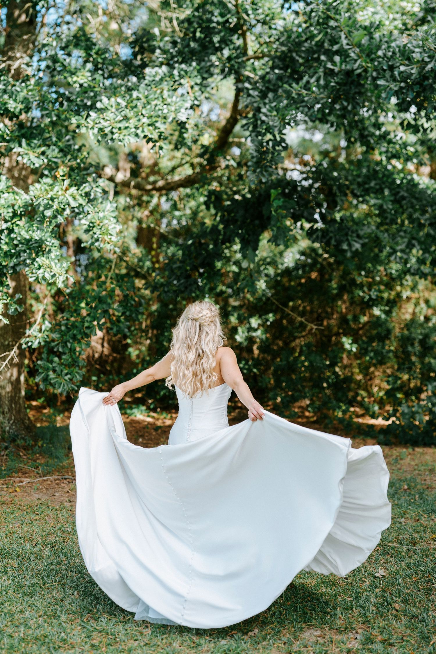 A flowing white wedding dress twirls gracefully against a lush green garden backdrop.