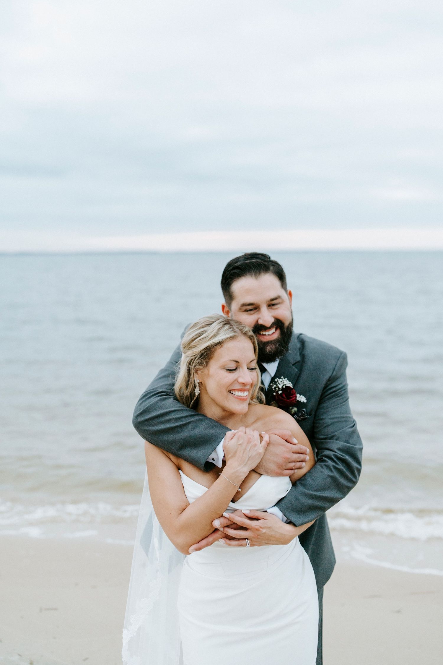 A joyful couple shares an intimate moment while embracing on a cloudy beach.