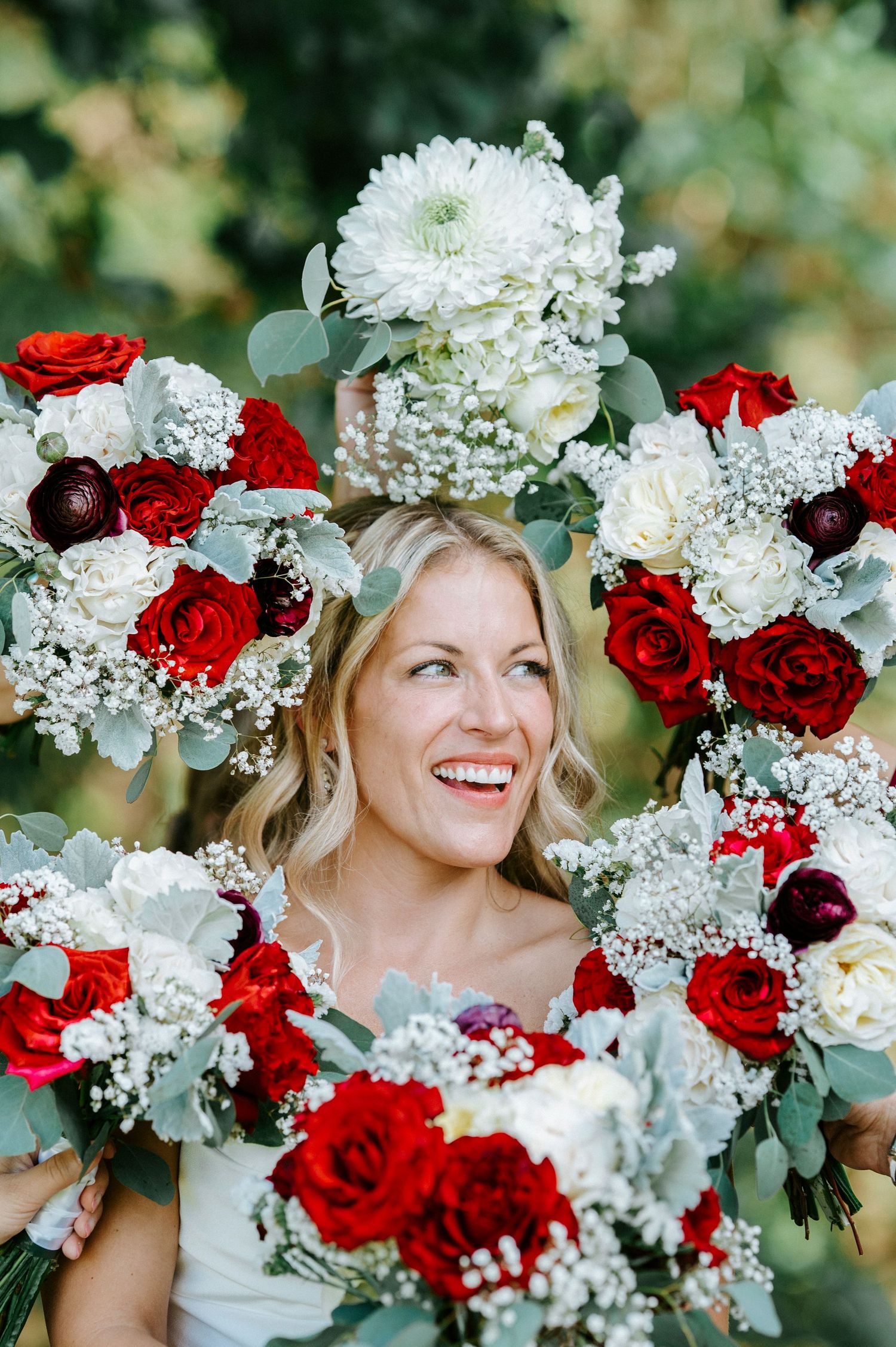 Bridal portrait with stunning red and white floral arrangements featuring roses and baby's breath.