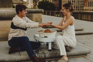 Couple shares an intimate moment while making pottery together on outdoor steps of a historic building.