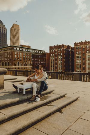 Couple sharing a casual rooftop meal against an urban backdrop of historic brick buildings and modern skyscrapers.