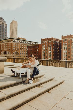 Couple sitting together on concrete steps of an urban rooftop with brick buildings in the background.