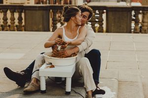 Two people share an intimate moment while working with clay on a rooftop terrace.