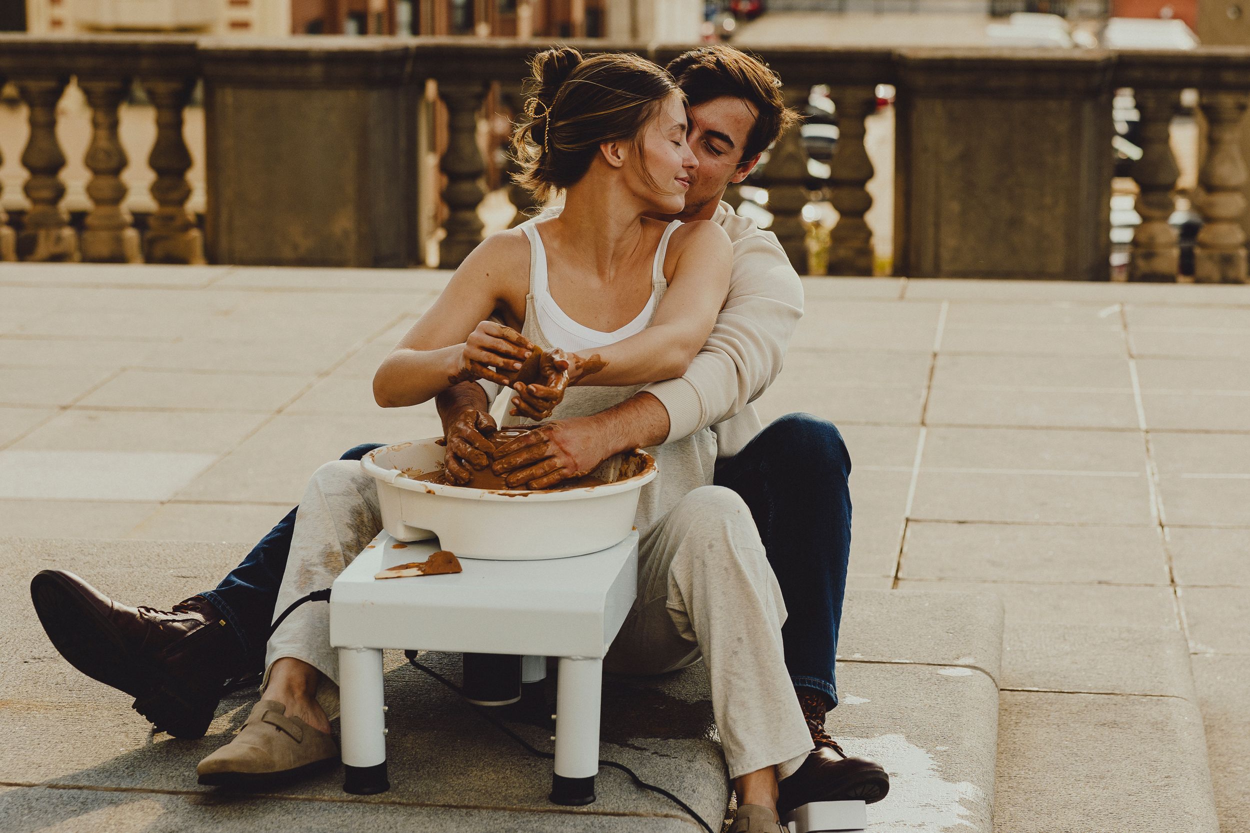 Two people share an intimate moment while working with clay on a rooftop terrace.