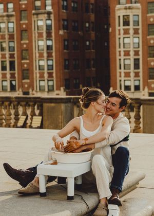 Romantic pottery session on rooftop terrace with historic brick buildings in background.