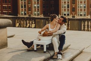 Romantic pottery making session on stone steps with city architecture in the background.