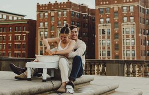 Two people lounging on stone steps sharing an intimate moment against an urban backdrop.