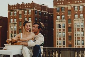 A romantic pottery session takes place on an urban rooftop with brick buildings in background.
