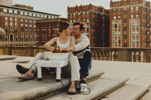 Candid rooftop scene showing a couple enjoying time together with vintage buildings in view.