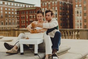Urban rooftop setting with two people sharing a casual moment against classic brick buildings.