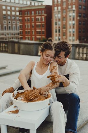 Couple playing with a ginger cat on a white table on an urban rooftop.