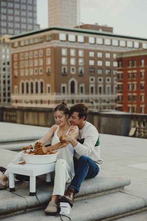 Couple enjoying a casual date on concrete steps with historic architecture in the background.