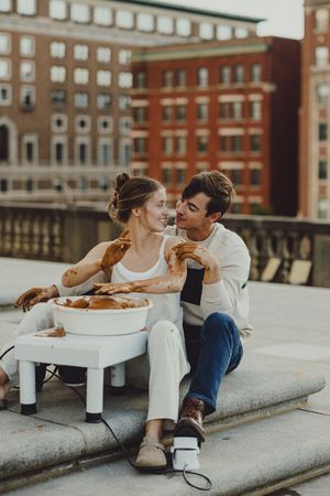 Intimate pottery making session on city rooftop with vintage architecture in background.