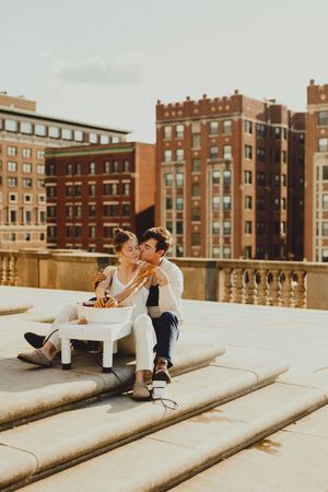 Two people share a romantic moment while making pottery on concrete steps.