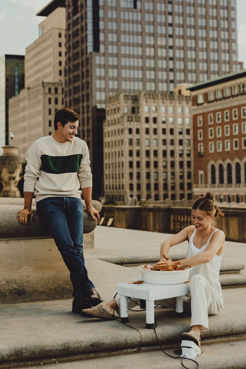 Couple enjoying a casual moment on concrete steps with city skyline in the background.