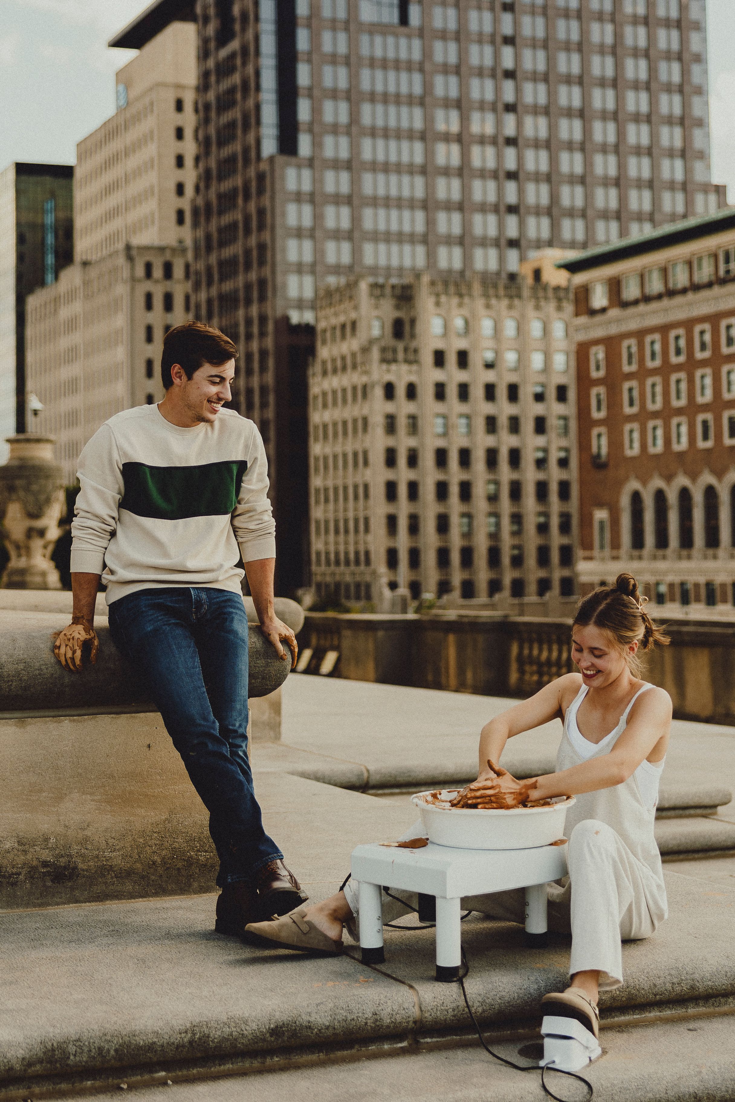 Couple enjoying a casual moment on concrete steps with city skyline in the background.