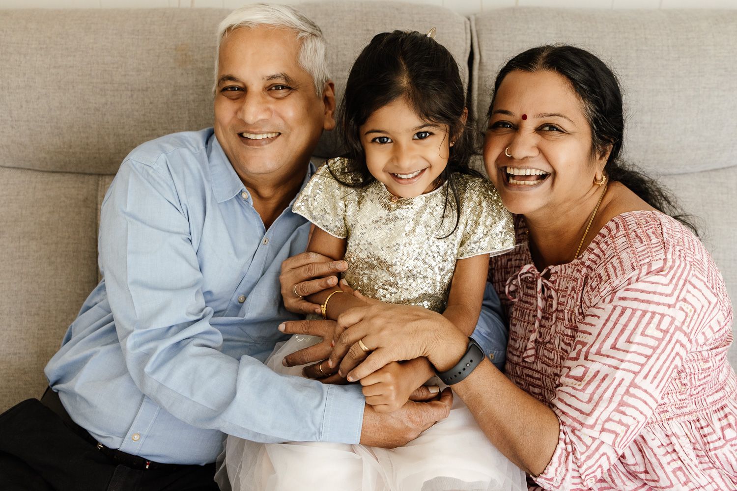 Grandparents smile with their granddaughter at their San Jose in-home session