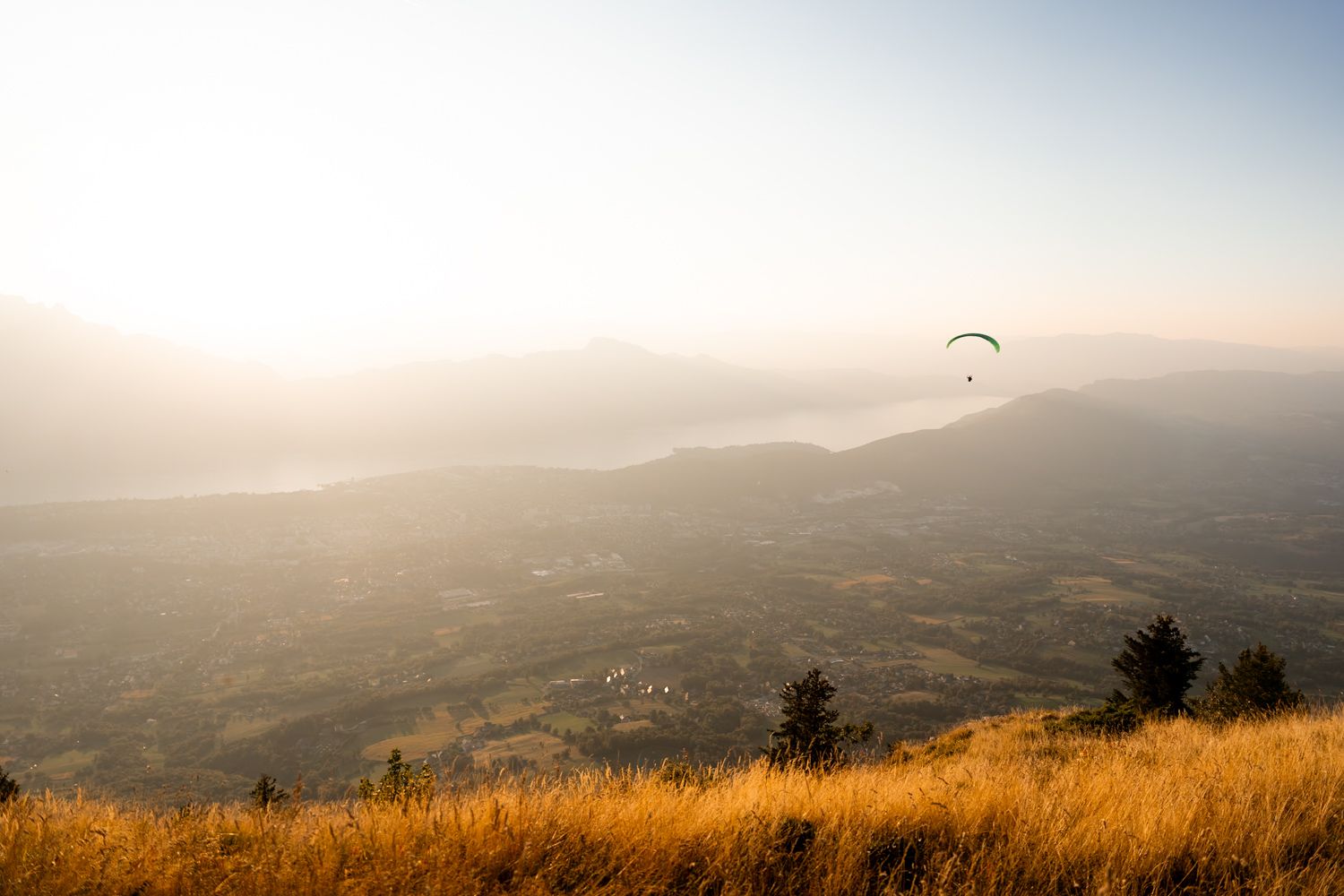 Coucher du soleil sur le lac du bourget depuis le belvédère du mont-revard avec un parapente au dessus du lac