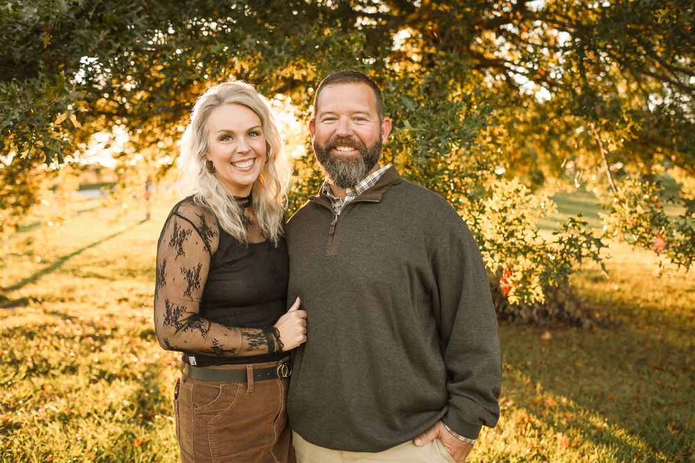 Couple embracing in front of trees during fall in Springfield MO