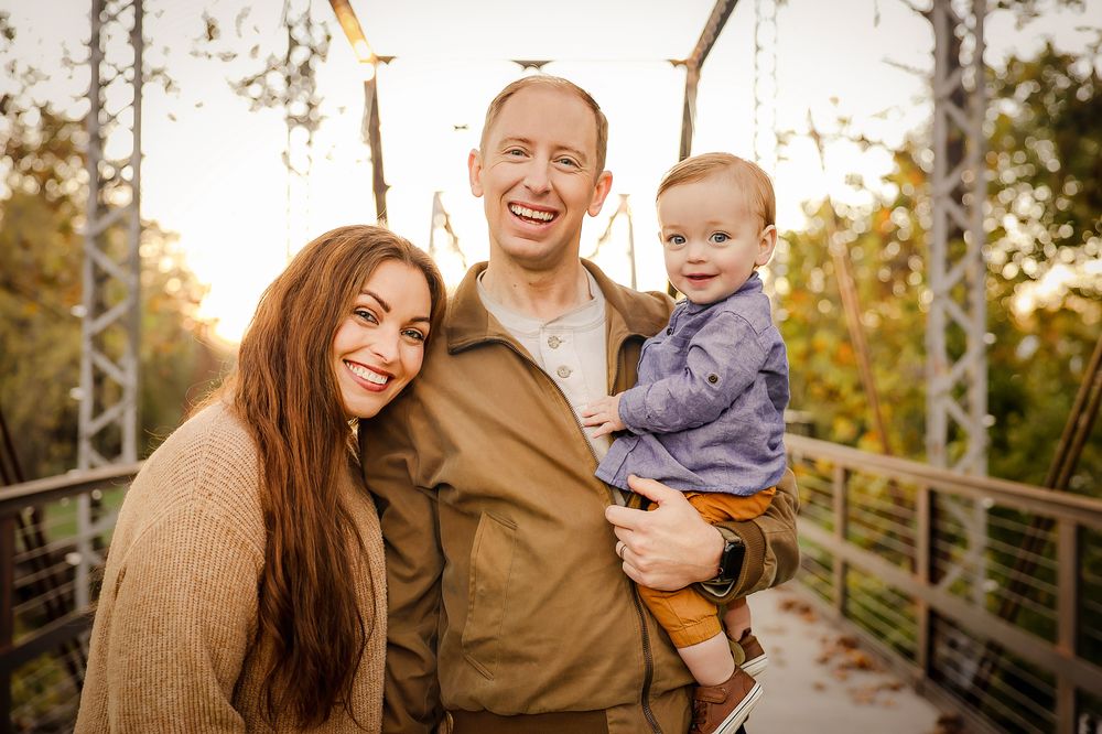 Family standing on bridge with fall background in Springfield MO