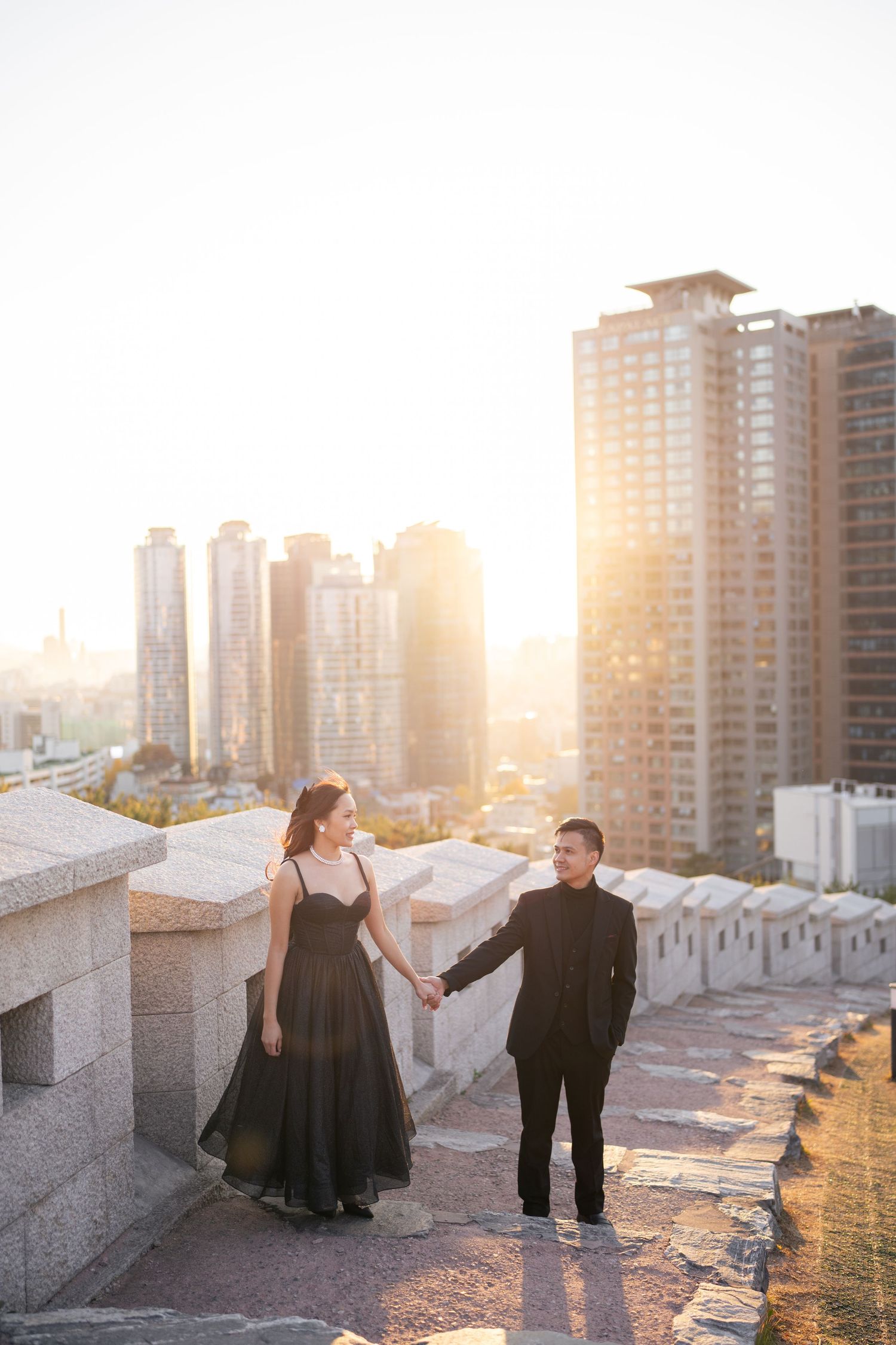A couple dances together on a rooftop at sunset with city high-rises in the background.