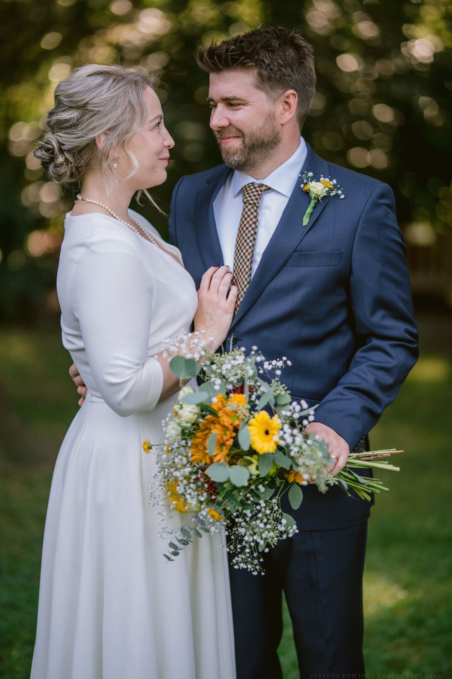 Romantic wedding portraits featuring a white dress, navy suit, and vibrant yellow floral bouquet.