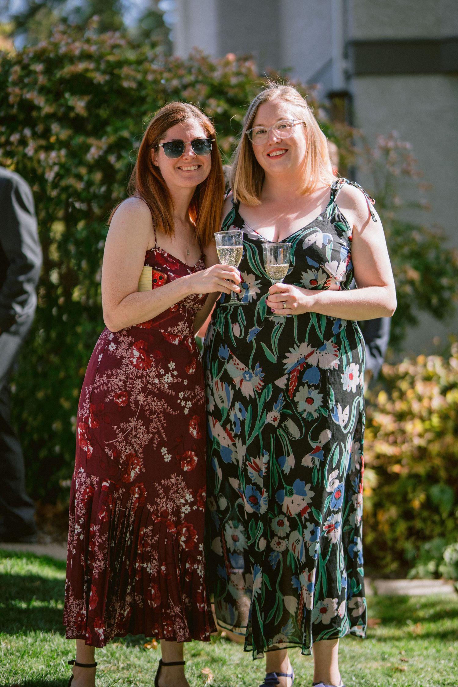 Friends in floral summer dresses gather together at a sunny outdoor event.